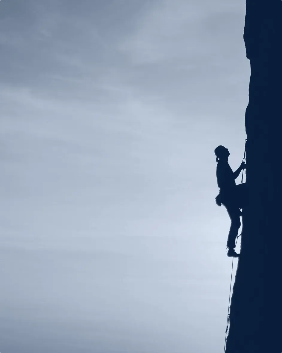une personne faisant de l'alpinisme, vu du flanc de la falaise