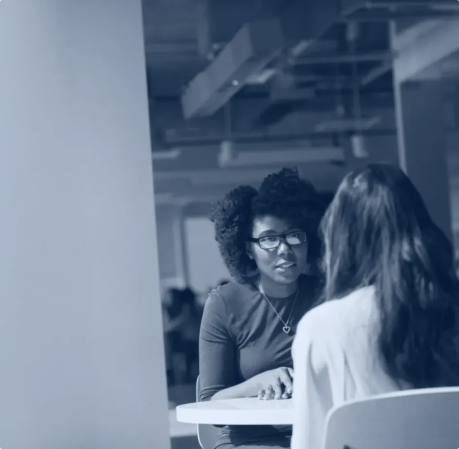 deux femmes en discussion assises de part et d'autre d'une table